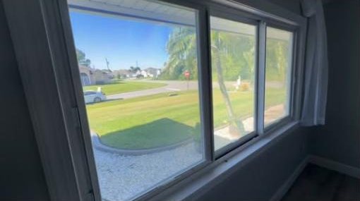 Three bedroom windows looking out to a front lawn and palm tree